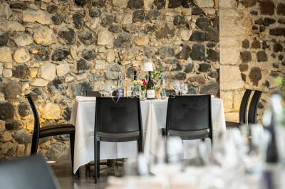 Tables dressées avec nappes blanches et chaises en bois sous des voiles d'ombrage dans une cour extérieure ensoleillée.