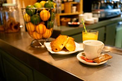 Façade d'un café-restaurant avec terrasse, chaises rouges et tables rondes, éclairage chaleureux à l'intérieur.