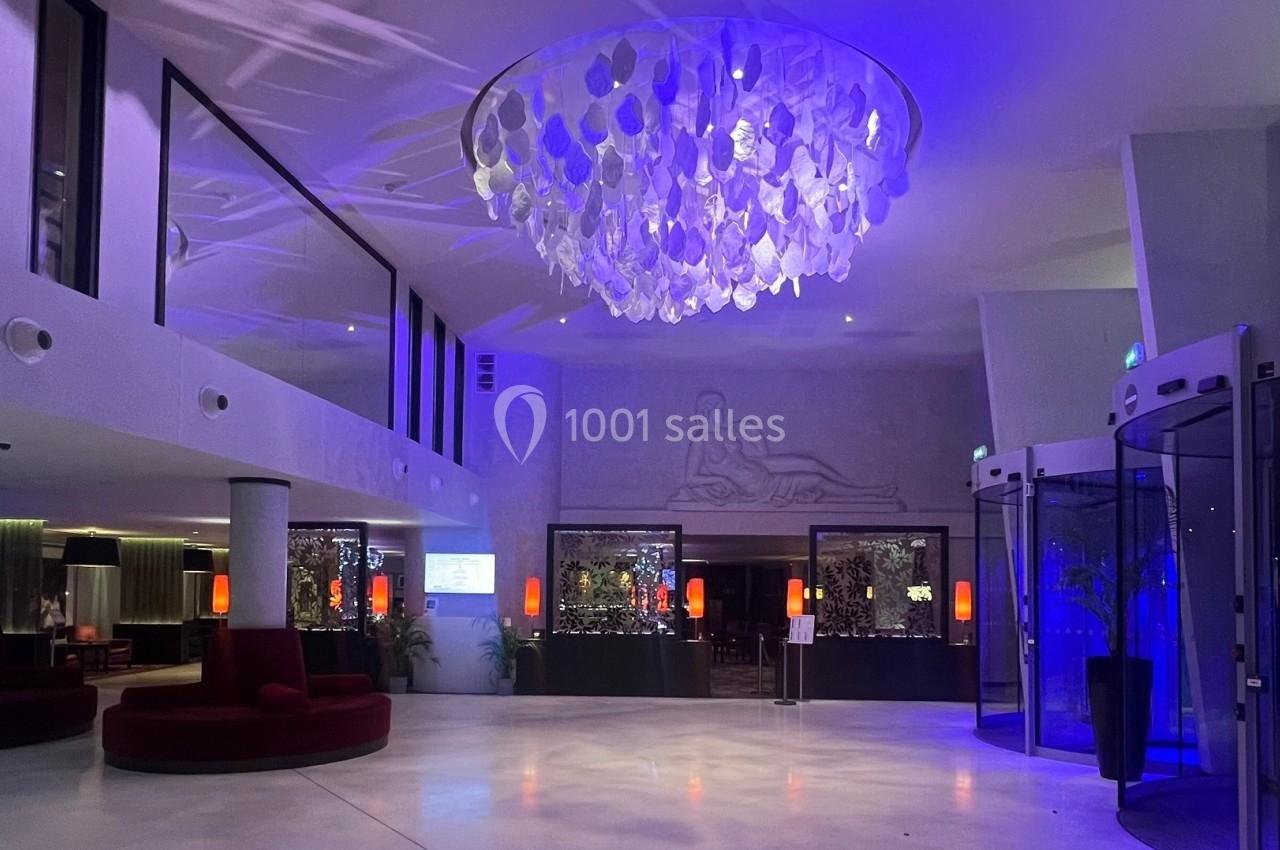 Hall d'entrée moderne avec un grand lustre décoratif, éclairage bleu et mobilier contemporain.