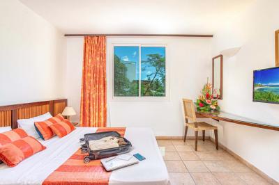 Salle de réunion avec tables disposées en U, chaises bleues et rouges, éclairage au plafond et sol carrelé beige.