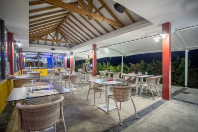 Salle de réunion avec tables disposées en U, chaises bleues et rouges, éclairage au plafond et sol carrelé beige.