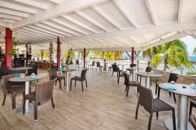 Chambre lumineuse avec lit double, mobilier en bois, télévision et balcon offrant une vue sur des palmiers.