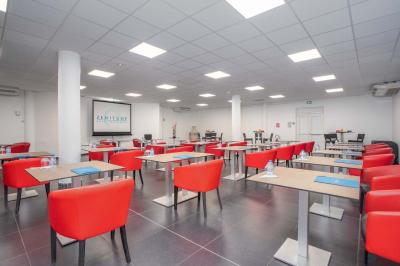 Chambre lumineuse avec lit double, mobilier en bois, télévision et balcon offrant une vue sur des palmiers.