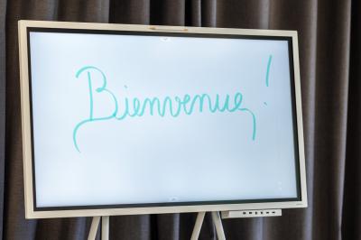 Chambre lumineuse avec lit double, mobilier en bois, télévision et balcon offrant une vue sur des palmiers.