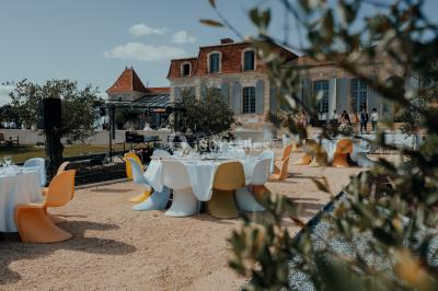 Grande table dressée en extérieur avec vaisselle, décorations florales et citrons, entourée de chaises en bois.