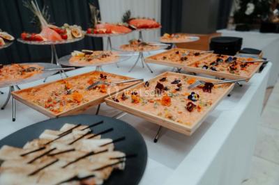 Grande table dressée en extérieur avec vaisselle, décorations florales et citrons, entourée de chaises en bois.