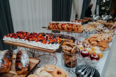 Grande table dressée en extérieur avec vaisselle, décorations florales et citrons, entourée de chaises en bois.