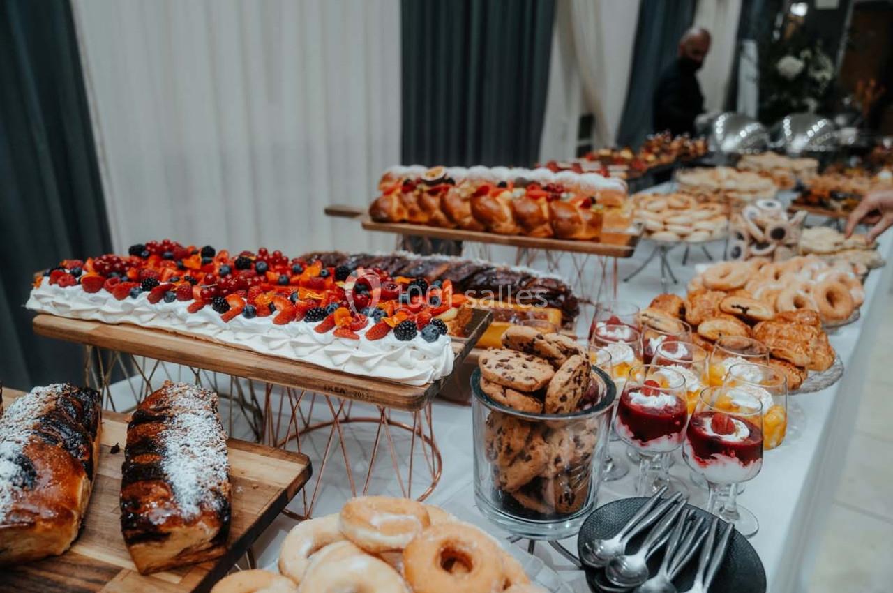Table garnie de desserts variés, incluant gâteaux, tartes aux fruits, biscuits, verrines et viennoiseries.