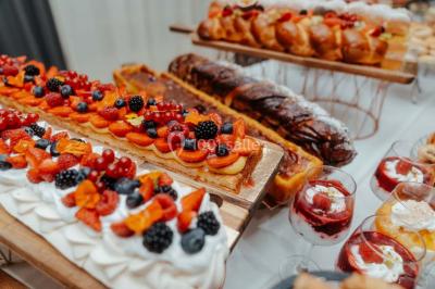 Grande table dressée en extérieur avec vaisselle, décorations florales et citrons, entourée de chaises en bois.