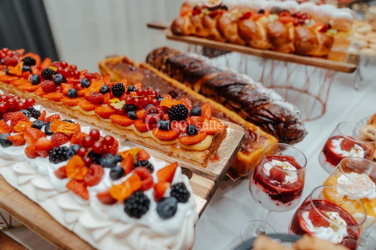 Plateau de desserts variés comprenant tartes aux fruits, pâtisseries et verrines sur une table de présentation.