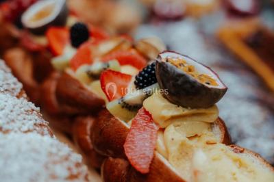 Grande table dressée en extérieur avec vaisselle, décorations florales et citrons, entourée de chaises en bois.