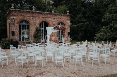 Grande table dressée en extérieur avec vaisselle, décorations florales et citrons, entourée de chaises en bois.