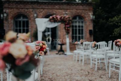 Grande table dressée en extérieur avec vaisselle, décorations florales et citrons, entourée de chaises en bois.