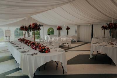 Grande table dressée en extérieur avec vaisselle, décorations florales et citrons, entourée de chaises en bois.