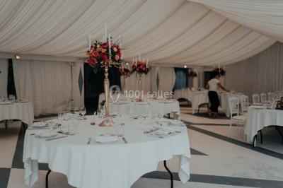 Grande table dressée en extérieur avec vaisselle, décorations florales et citrons, entourée de chaises en bois.
