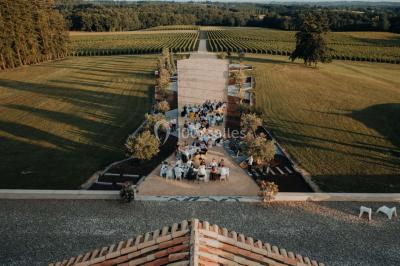 Grande table dressée en extérieur avec vaisselle, décorations florales et citrons, entourée de chaises en bois.