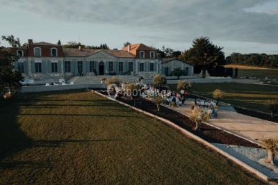 Grande table dressée en extérieur avec vaisselle, décorations florales et citrons, entourée de chaises en bois.