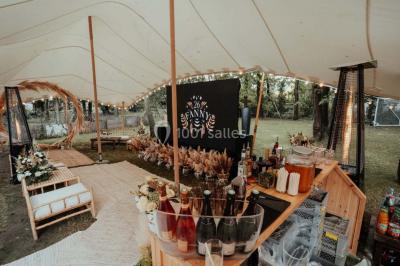 Grande table dressée en extérieur avec vaisselle, décorations florales et citrons, entourée de chaises en bois.