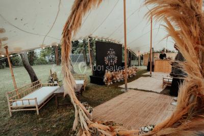 Grande table dressée en extérieur avec vaisselle, décorations florales et citrons, entourée de chaises en bois.