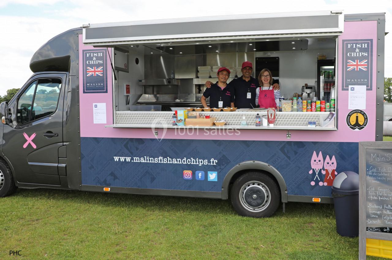 Camion de restauration rapide proposant des fish and chips, avec trois personnes souriantes à l'intérieur.