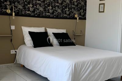 Salle lumineuse avec tables rectangulaires, chaises noires et verrerie suspendue, donnant sur de grandes fenêtres.