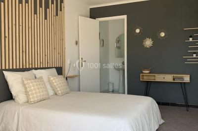 Salle lumineuse avec tables rectangulaires, chaises noires et verrerie suspendue, donnant sur de grandes fenêtres.