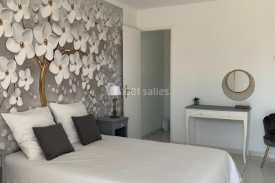 Salle lumineuse avec tables rectangulaires, chaises noires et verrerie suspendue, donnant sur de grandes fenêtres.