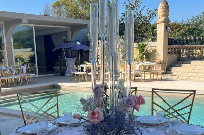 Salle lumineuse avec tables rectangulaires, chaises noires et verrerie suspendue, donnant sur de grandes fenêtres.