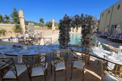 Salle lumineuse avec tables rectangulaires, chaises noires et verrerie suspendue, donnant sur de grandes fenêtres.