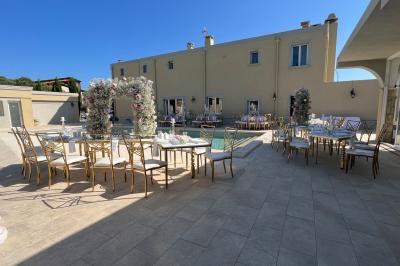 Salle lumineuse avec tables rectangulaires, chaises noires et verrerie suspendue, donnant sur de grandes fenêtres.