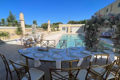 Salle lumineuse avec tables rectangulaires, chaises noires et verrerie suspendue, donnant sur de grandes fenêtres.