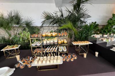 Salle lumineuse avec tables rectangulaires, chaises noires et verrerie suspendue, donnant sur de grandes fenêtres.