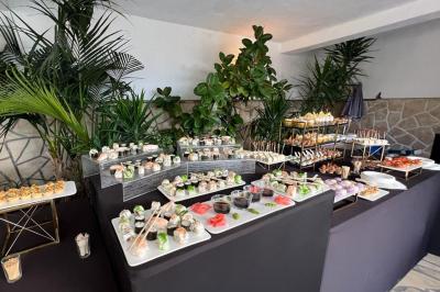 Salle lumineuse avec tables rectangulaires, chaises noires et verrerie suspendue, donnant sur de grandes fenêtres.