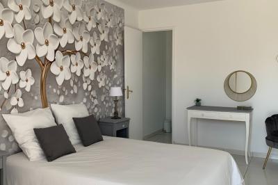 Chambre lumineuse avec lit double, décoration murale en bois et accès à une salle de bain attenante.