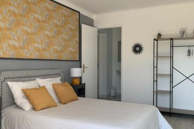 Chambre lumineuse avec lit double, décoration murale en bois et accès à une salle de bain attenante.