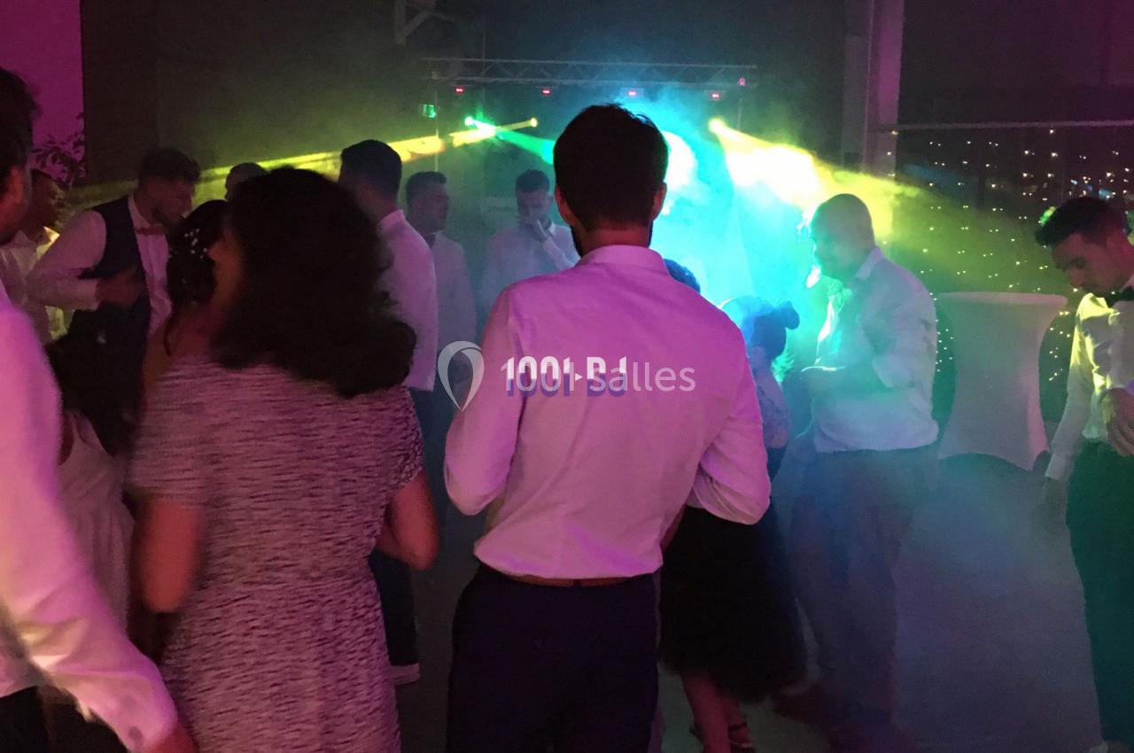 Des personnes dansent sous des lumières colorées dans une ambiance festive en intérieur.