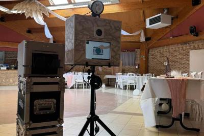 Miroir interactif encadré de lumières, posé sur un tapis rouge avec des chapeaux colorés à proximité.