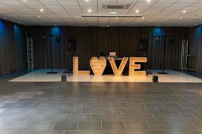 Miroir interactif encadré de lumières, posé sur un tapis rouge avec des chapeaux colorés à proximité.