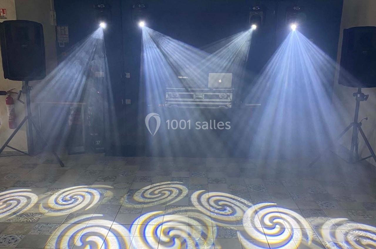 Effets lumineux avec faisceaux blancs et motifs circulaires projetés sur le sol dans une salle équipée de haut-parleurs.