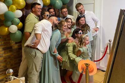 Miroir interactif encadré de lumières, posé sur un tapis rouge avec des chapeaux colorés à proximité.