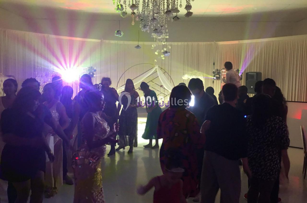 Groupe de personnes dans une salle de réception décorée, éclairée par des lumières colorées, lors d'un événement festif.