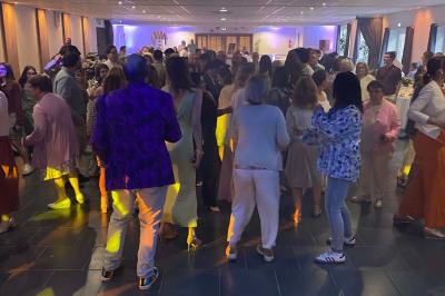 Des personnes dansent sous des lumières colorées dans une ambiance festive en intérieur.