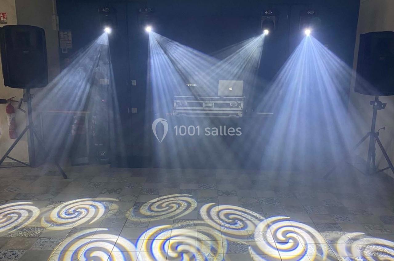 Jeux de lumières projetant des motifs en spirale sur un sol carrelé, avec une table de mixage en arrière-plan.