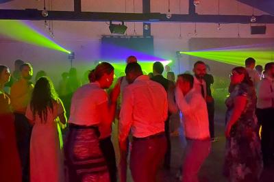 Des personnes dansent sous des lumières colorées dans une ambiance festive en intérieur.