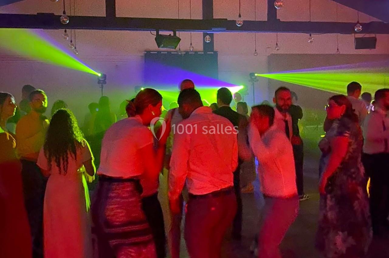 Des personnes dansent dans une salle sombre éclairée par des faisceaux lumineux colorés.