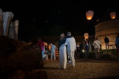 Un couple de dos observe des lanternes volantes dans un cadre nocturne entouré de convives.