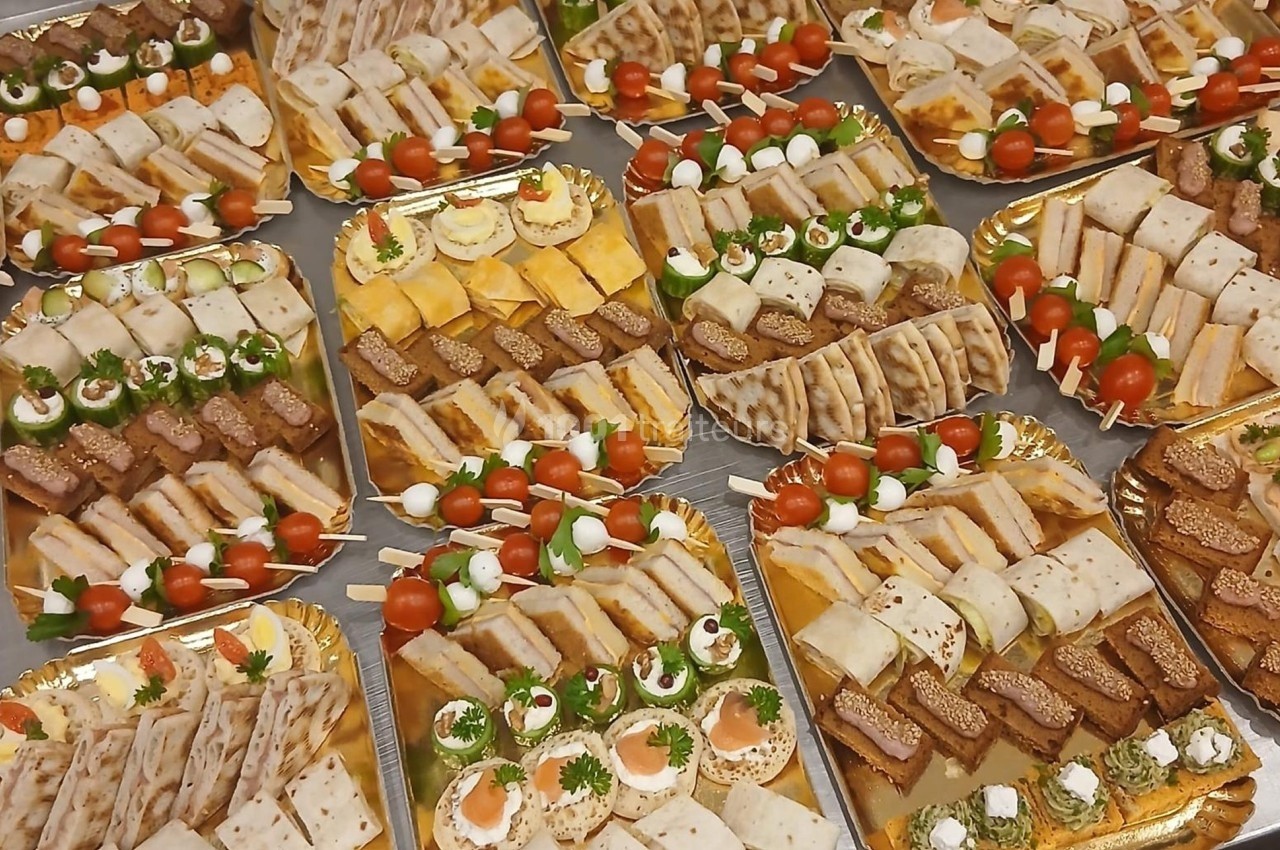 Plateaux garnis de divers amuse-bouches, incluant canapés, roulés, brochettes et mini-sandwichs.
