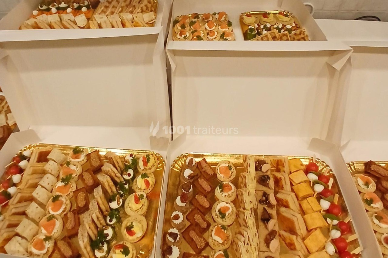 Plateaux garnis d'amuse-bouches variés, incluant canapés, mini-sandwichs, roulés et bouchées apéritives.