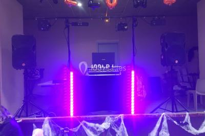 Poste de DJ éclairé par des lumières violettes, entouré de décorations d'Halloween et de toiles d'araignée.