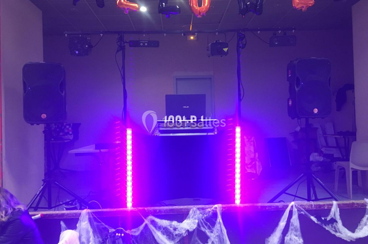 Poste de DJ éclairé par des lumières violettes, entouré de décorations d'Halloween et de toiles d'araignée.